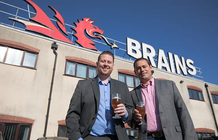 two men outside brains brewery with pints