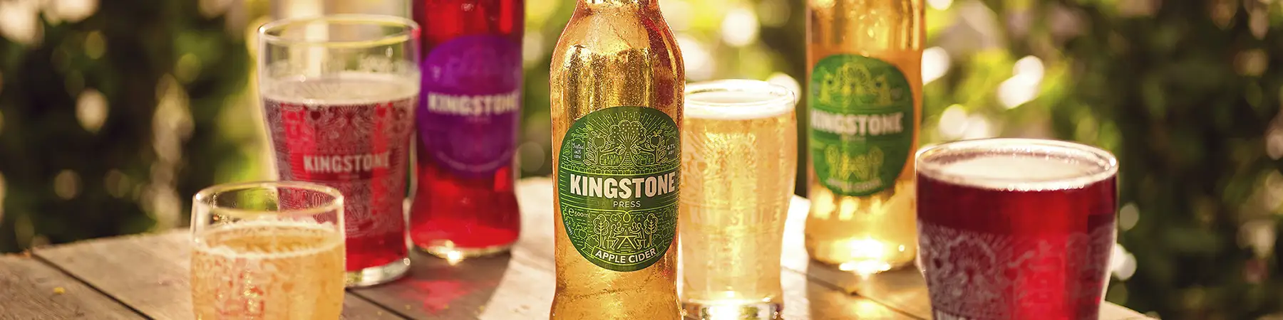 pints and bottles of Kingstons press ciders on table outdoors in sunshine
