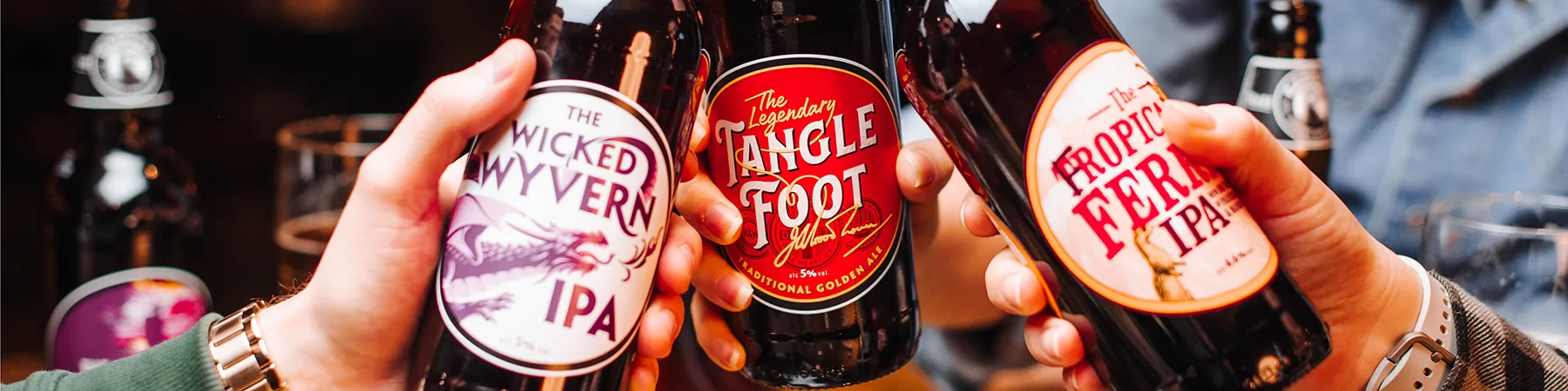 three people holding bottles of badger brewery beers