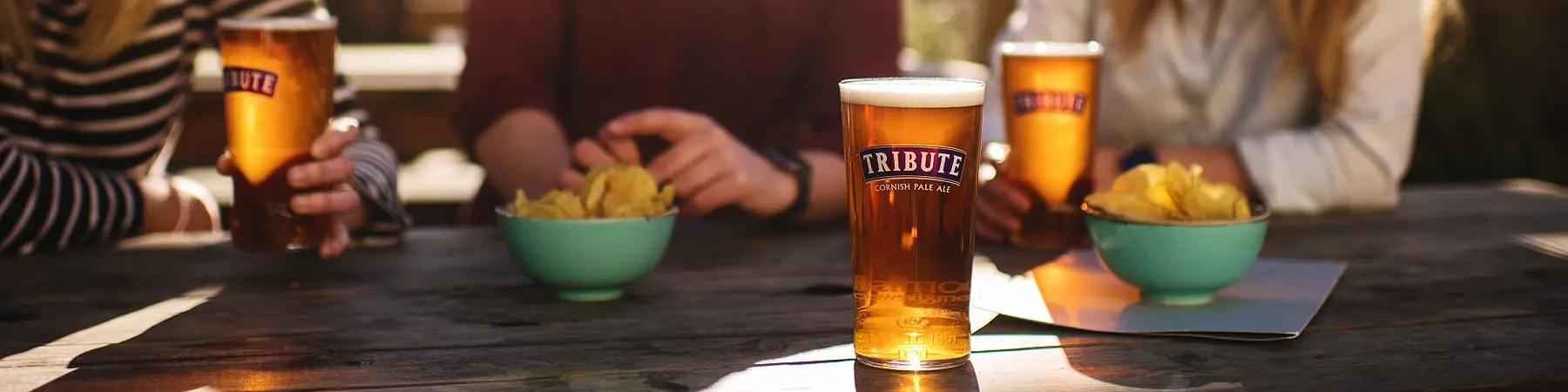 st Austell tribute beer on table in beer garden with bowls of crips