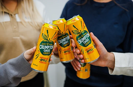 people saluting with cans of crumpton oaks apple cider