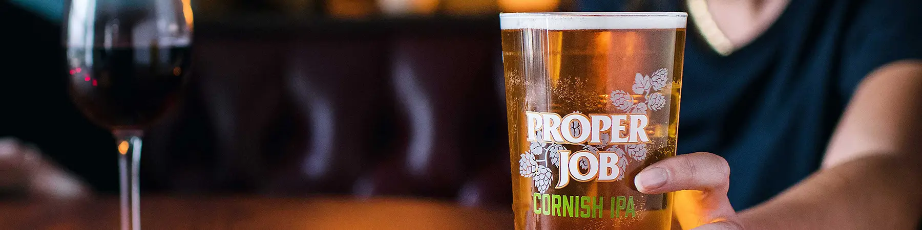 man holding pint of st Austell proper job ipa in pub