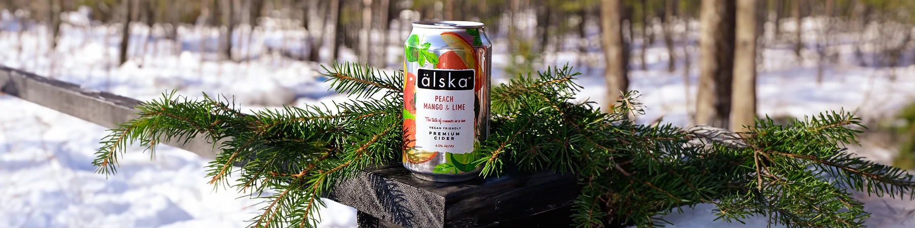can of alska peach, mango & lime cider outside next to snow and trees