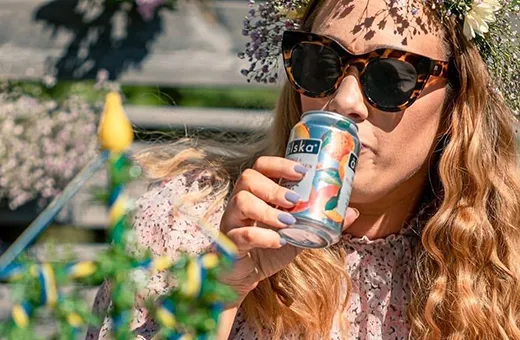 lady sipping can of alska peach, mango & lime cider in the sun